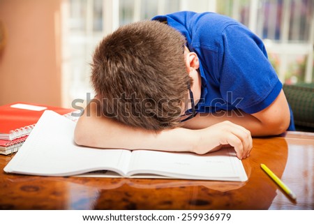 Little blond boy taking a nap in the middle of a difficult homework