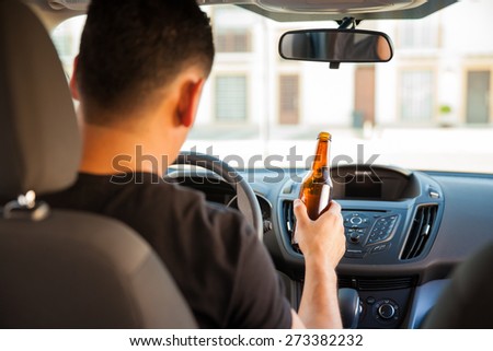 Rear view of a young man driving recklessly while drinking beer