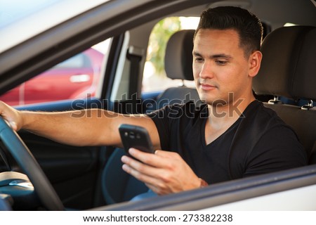 Portrait of a young reckless male driver using his cell phone behind the wheel