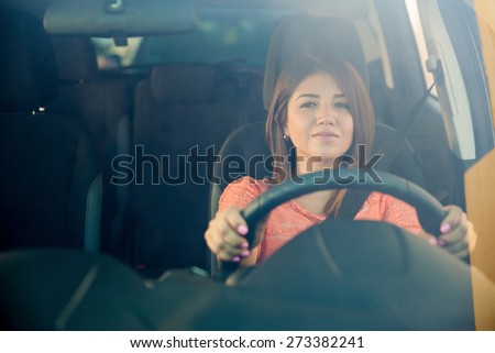 Portrait of a young Hispanic woman looking at the road, shot through the windshield