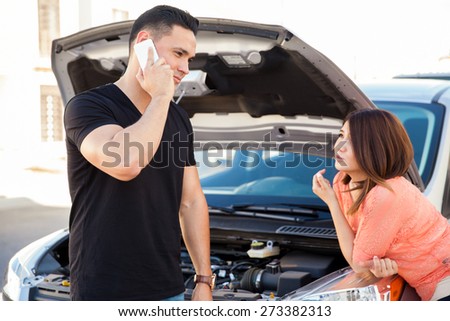Handsome young man using his phone to call for some road assistance for his car