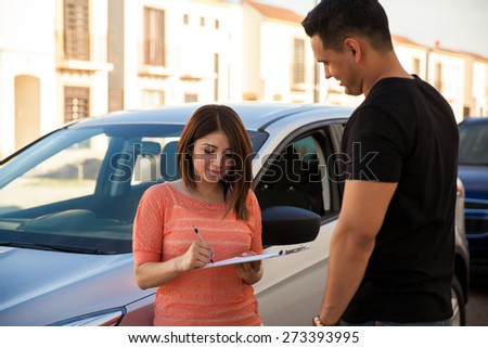 Pretty young woman signing a new car lease with a salesperson
