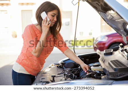 Pretty young brunette calling someone for help with her broken car