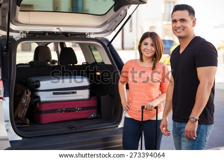 Couple of happy newlyweds with a loaded car and ready to begin their honeymoon trip