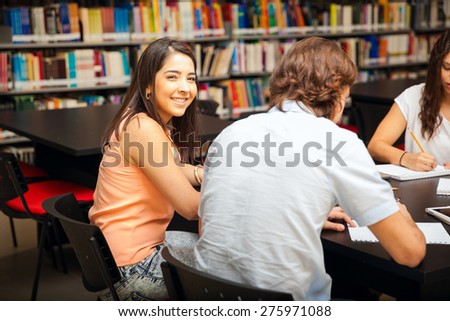 Portrait of a young brunette studying with a group of friends in the library