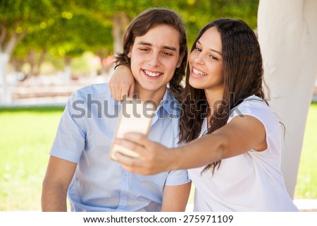 Cute couple of college students taking a selfie at school with a phone