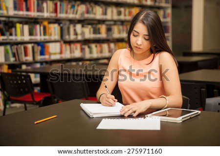 Pretty female university student doing some work at the school library