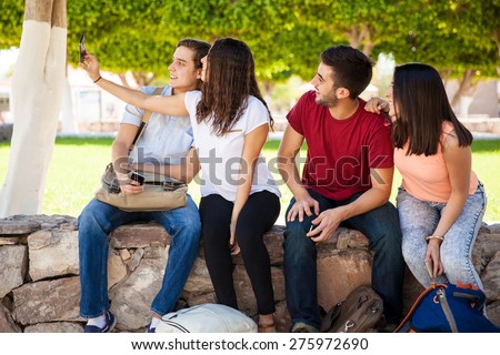 Group of college students hanging out at school and taking a selfie with a smartphone