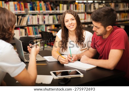 Portrait of a beautiful college student smiling while studying with her friends in the library