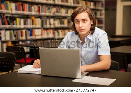 Portrait of a male college student using a laptop computer at school and making eye contact