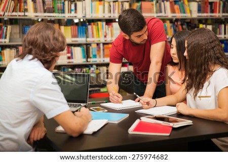 Male college student explaining some school work to his colleagues while studying in the library