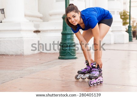 Pretty young brunette putting her inline skates on and getting ready for skating in the city