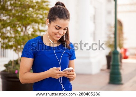 Happy female runner looking for the perfect song for her workout in the city