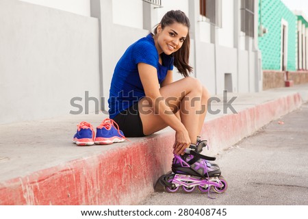 Beautiful Latin young woman putting her inline skates on, ready to go skating in the city