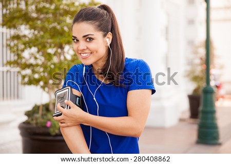 Portrait of a pretty Latin brunette wearing his phone in an armband and ready to workout with some music