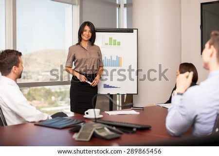 Portrait of a beautiful young Hispanic woman giving a presentation on a flipboard in a meeting room