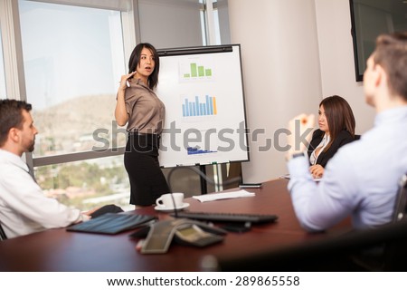 Pretty Latin businesswoman giving a presentation to a bunch of people in a meeting room