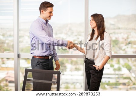 Profile view of a young handsome man giving a woman a handshake in a meeting room