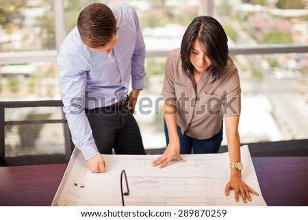 Couple of young architects analyzing a building plan in a meeting room