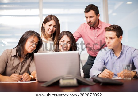 Portrait of a group of people looking at a laptop computer and doing some work in an office