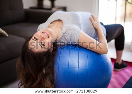 Pretty Hispanic pregnant woman using a stability ball at home for exercising during pregnancy