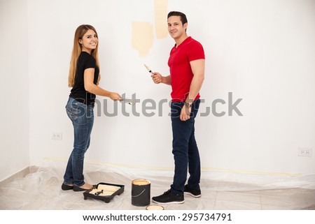 Full length portrait of a Hispanic couple painting and decorating their home