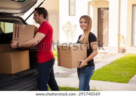 Cute young Hispanic couple loading their stuff in their car and moving to their new home