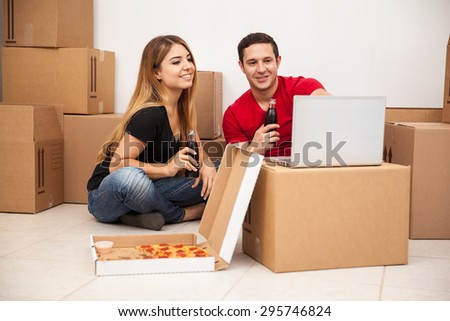 Attractive young couple moving into a new home and relaxing with pizza and a TV show in a laptop