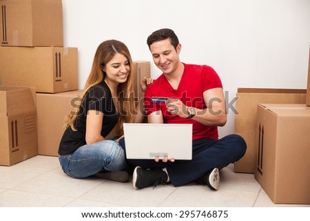 Portrait of a cute young couple using a credit card and a laptop to buy furniture for their new home