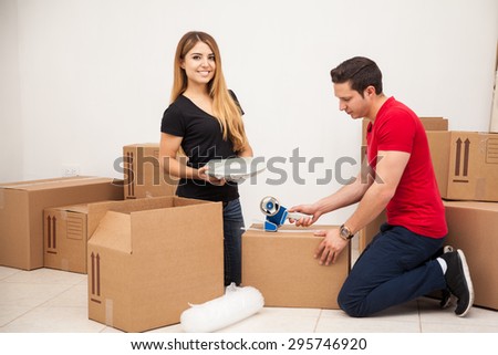 Happy young woman helping her boyfriend pack his things and move in to her apartment