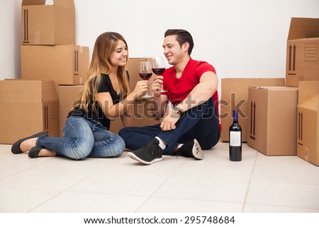 Attractive young Hispanic couple drinking wine and celebrating they just bought a new home