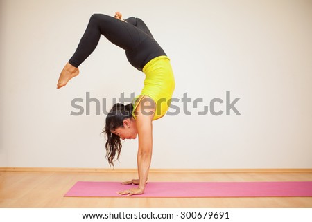 Pretty brunette doing a headstand with crossed legs during practice in a yoga studio