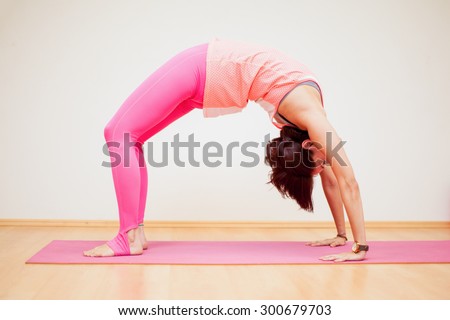 Young woman practicing a backbend yoga pose in a yoga studio