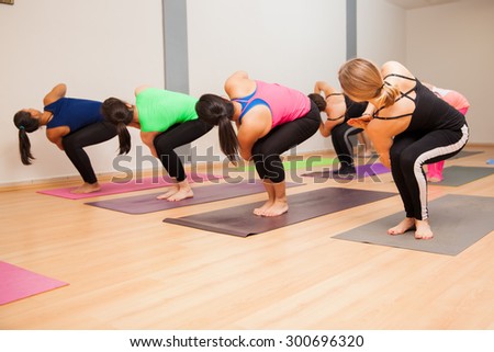 Group of young women doing a chair twist pose in a yoga studio