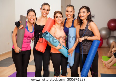 Five young Hispanic women smiling and having fun in a yoga studio