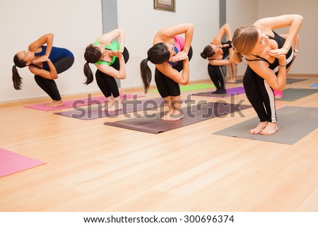 Large group of women holding the chair pose during their yoga class. Lots of copy space