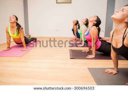 Wide angle view of a female yoga instructor demonstrating a pose to a group of women in a yoga studio