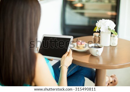 Point of view of a young brunette using a tablet computer and relaxing in a cake shop
