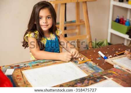 Portrait of a gorgeous little girl with an apron drawing something for art class
