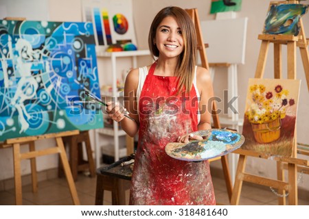 Portrait of a gorgeous female artist working on several art projects on her studio