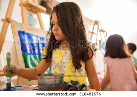 Portrait of a beautiful little artist working on a painting for art class