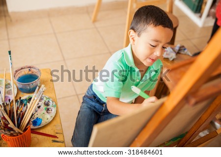 High angle view of a cute little boy working on a painting for art class at school