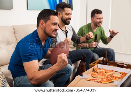 Profile view of a group of male friends cheering for their football team while watching the game at home