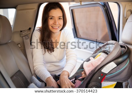 Portrait of a gorgeous young mother securing her baby on a child seat before driving