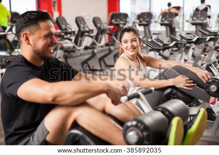 Portrait of a pretty brunette laughing and having fun with his boyfriend while working out together in a gym