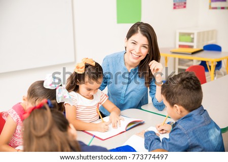 Portrait of a gorgeous Hispanic preschool teacher teaching her students in a classroom