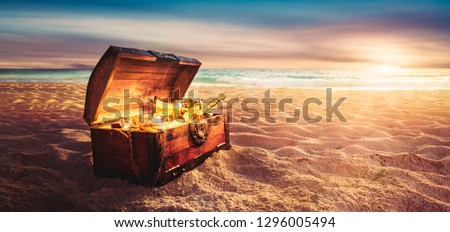 open treasure chest filled with golden items at sunset