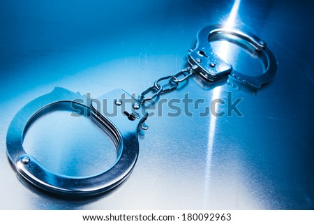 Closed handcuffs, security concept on a metallic background and dramatic lighting