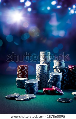 Poker Chips on a gaming table with dramatic lighting Poker Chips on a gaming table with dramatic lighting