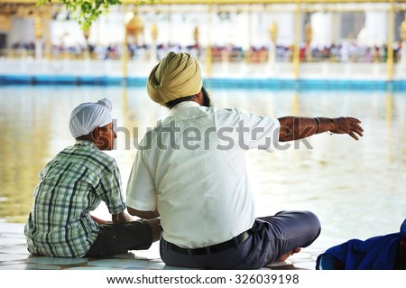 Amritsar, India - September  27, 2013: Sikh father and son were sitting by the pool in Golden Temple for pilgrimage in Amritsar in the state of Punjab, India.